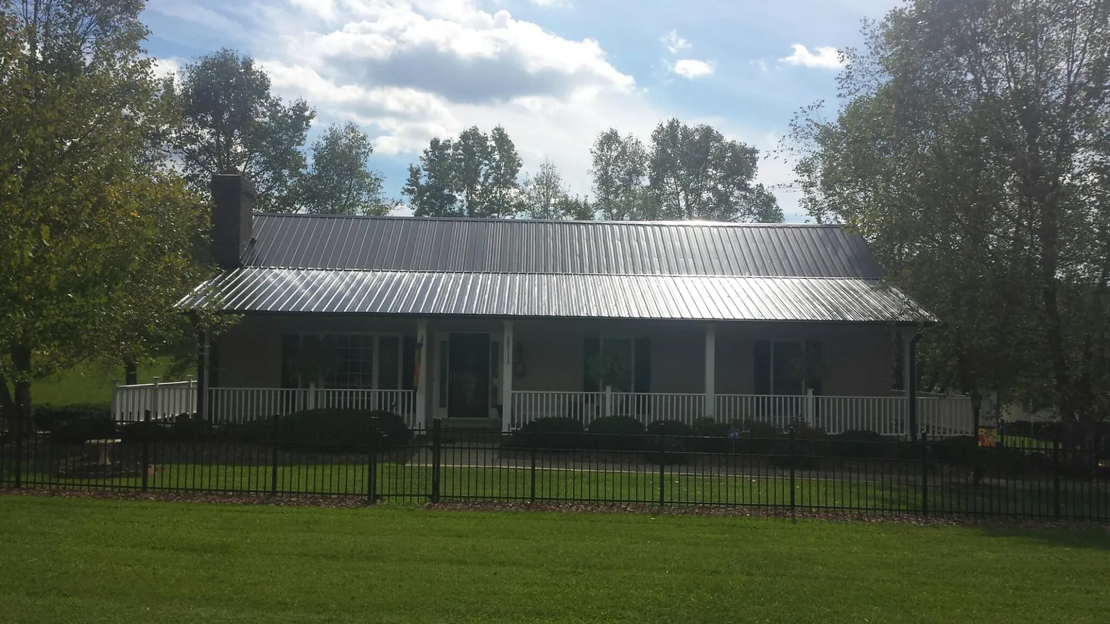 Gray metal roof on a brick ranch with a full width front porch — Gutter Guard Installation work by our crew in Erwin